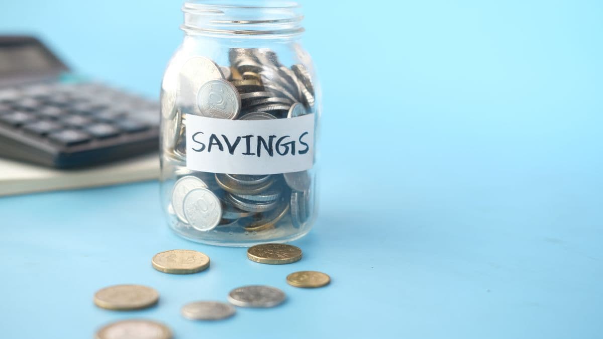 A savings jar beside a calculator for setting savings goals